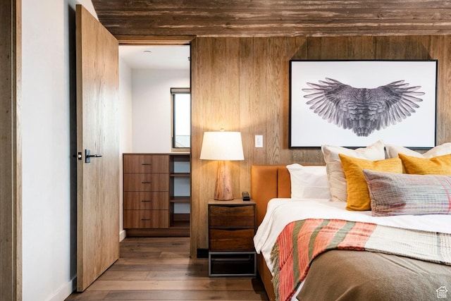 bedroom with wood-type flooring, baseboards, and wood walls