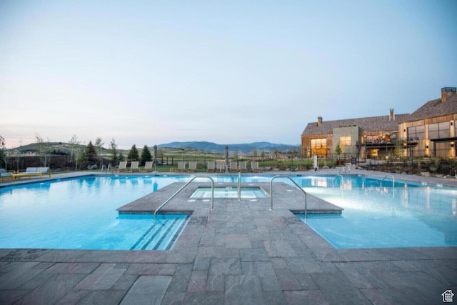 community pool with a patio, a mountain view, and a hot tub