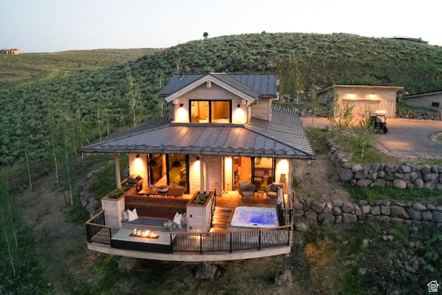 back of house featuring an outdoor fire pit, a standing seam roof, metal roof, and a forest view