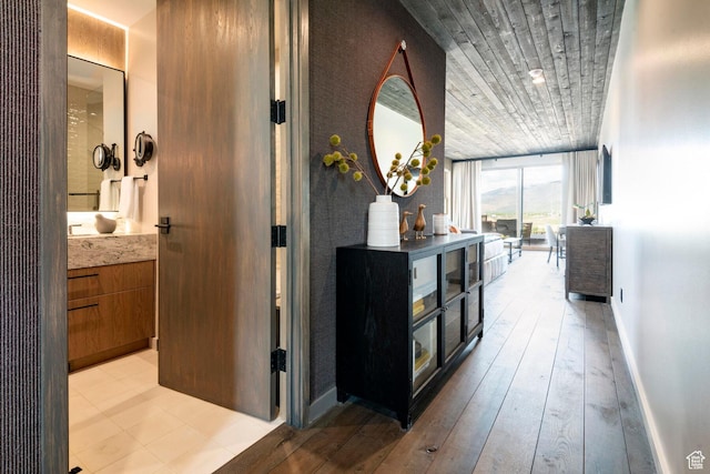 corridor featuring wood ceiling, a wall of windows, light wood-style floors, and baseboards