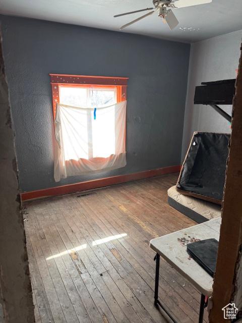 unfurnished bedroom with hardwood / wood-style flooring, baseboards, and a ceiling fan