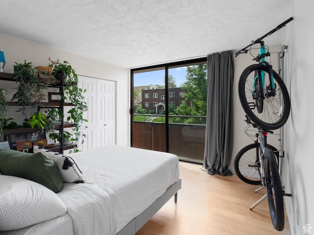 141 E Second Ave N Unit 502, Salt Lake City, UT 84103 - bedroom with a textured ceiling, light wood-style floors, access to exterior, a closet, and expansive windows