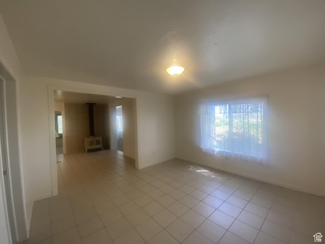 50 S 400 E, Myton, UT 84052 - unfurnished room with light tile patterned flooring, baseboards, and a wood stove