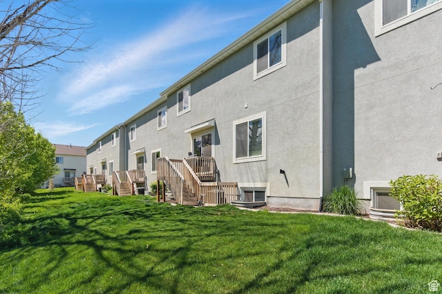 rear view of house featuring stucco siding, a lawn, stairs, and a residential view