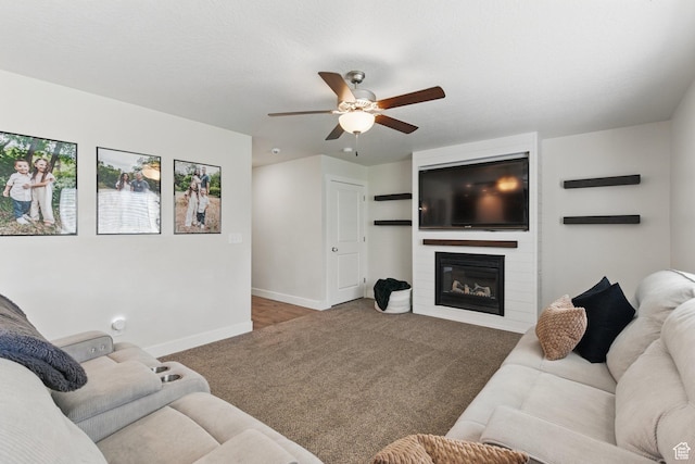 carpeted living area with ceiling fan, baseboards, and a fireplace
