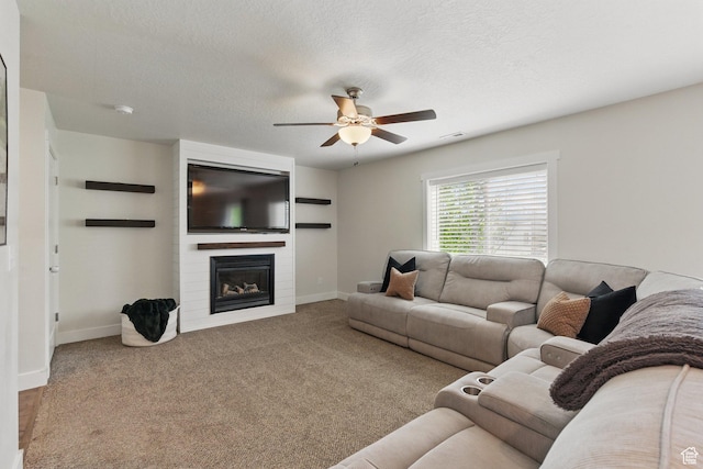 living area with ceiling fan, baseboards, a large fireplace, carpet, and a textured ceiling