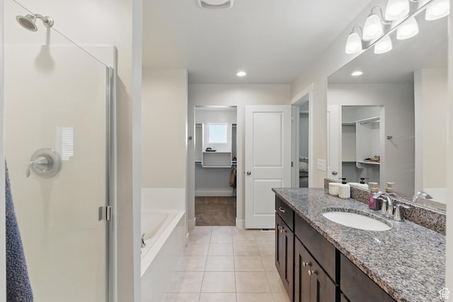 full bathroom with a stall shower, tile patterned flooring, a bath, vanity, and a walk in closet