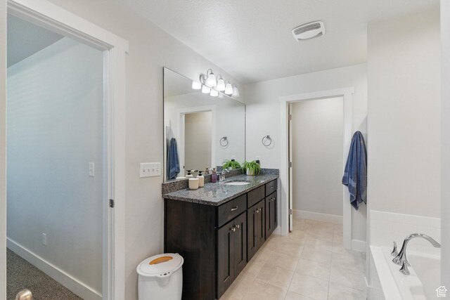 bathroom with vanity, a bath, baseboards, and tile patterned flooring