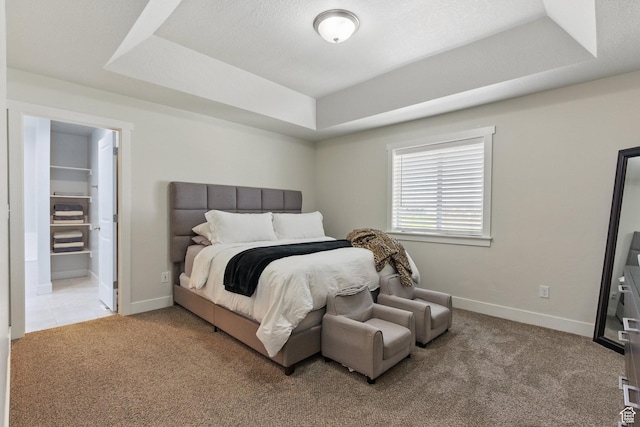 bedroom featuring a tray ceiling, light carpet, and baseboards