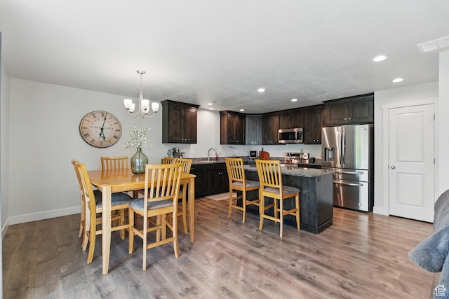 dining space with a chandelier, recessed lighting, baseboards, and light wood-style flooring