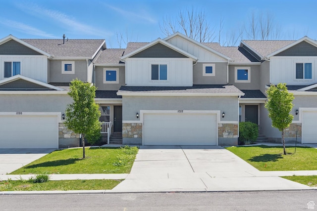 view of front of home with stone siding, concrete driveway, a front yard, and board and batten siding