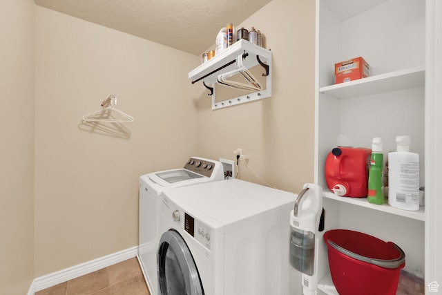 laundry room featuring washing machine and dryer, baseboards, and light tile patterned flooring