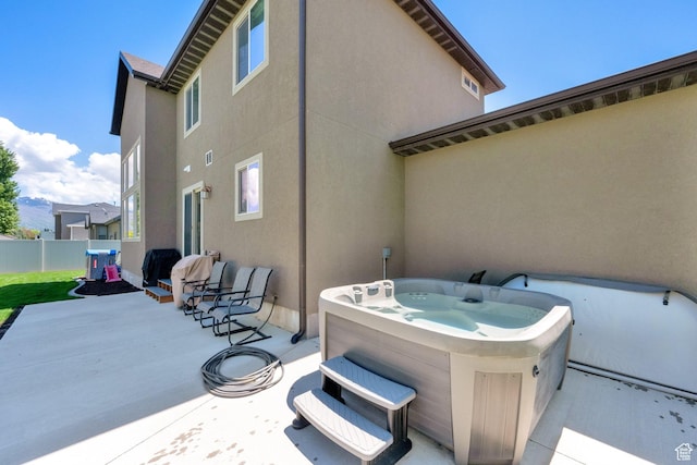view of patio featuring a hot tub and fence