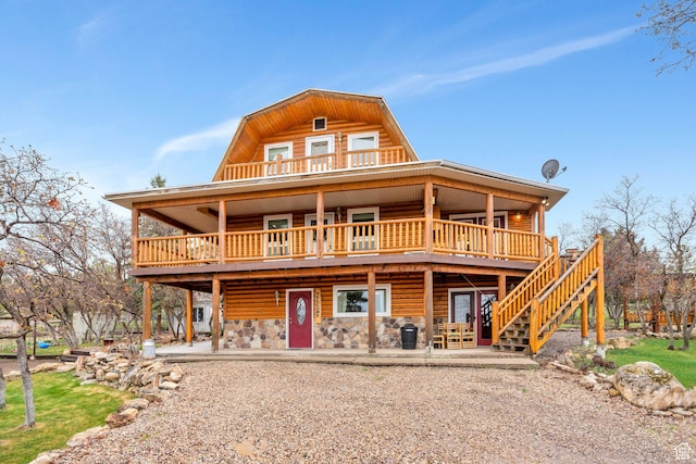 rear view of house with a gambrel roof, a deck, stairway, and a patio
