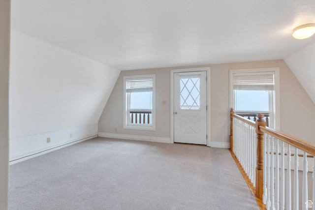 bonus room with vaulted ceiling, light colored carpet, and baseboards