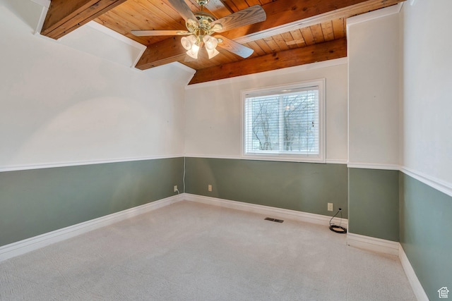 carpeted spare room featuring wood ceiling, ceiling fan, beamed ceiling, and baseboards