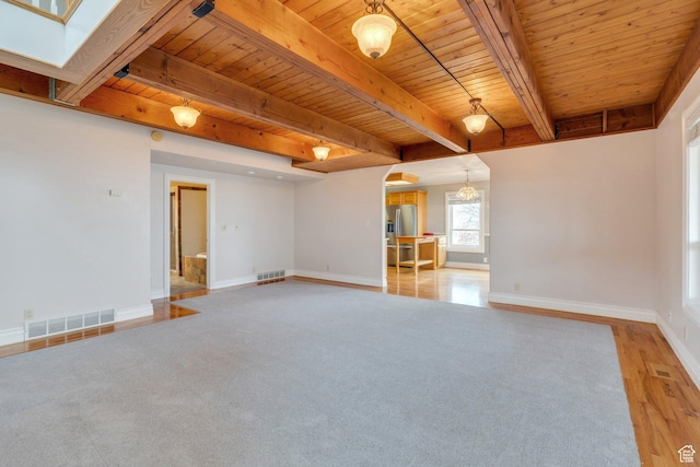 unfurnished living room featuring wood ceiling, arched walkways, baseboards, beamed ceiling, and a chandelier