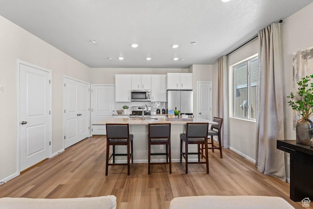 351 N Riverside Dr Unit 978, Saratoga Springs, UT 84045 - kitchen with appliances with stainless steel finishes, a sink, light wood-type flooring, a breakfast bar, and recessed lighting