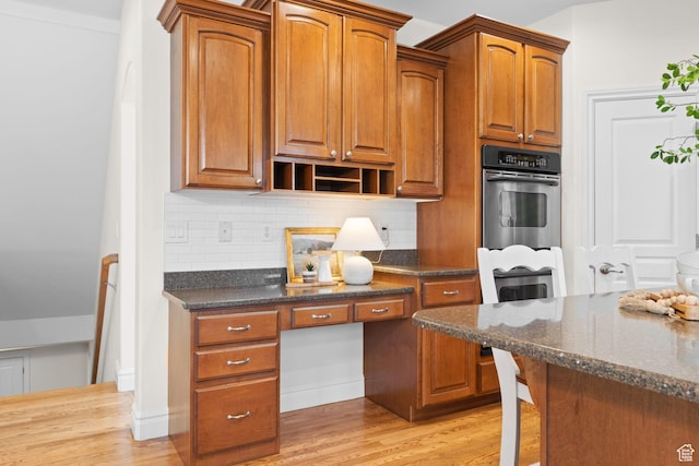 512 Glendon Way, Pleasant Grove, UT 84062 - kitchen featuring oven, tasteful backsplash, light wood-type flooring, dark stone countertops, and brown cabinetry