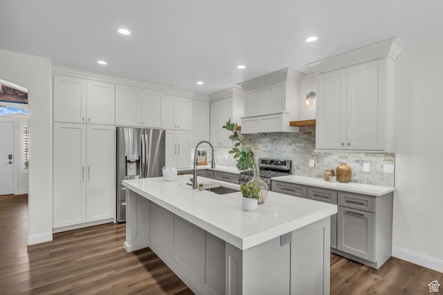 kitchen with stainless steel appliances, a sink, decorative backsplash, light countertops, and dark wood finished floors