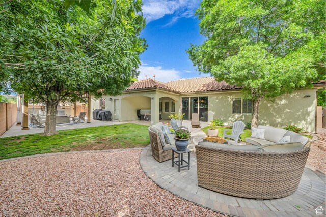 rear view of property with stucco siding, outdoor lounge area, a tile roof, a patio, and fence