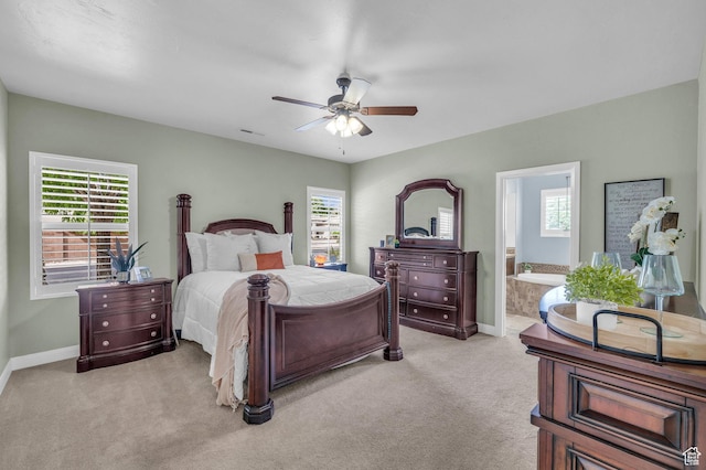 bedroom with multiple windows, light carpet, baseboards, and ensuite bathroom