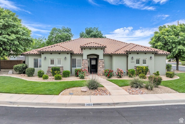 mediterranean / spanish house with stucco siding, a tile roof, and stone siding
