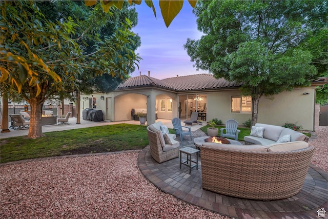 rear view of house with an outdoor living space with a fire pit, stucco siding, a patio area, and a tile roof