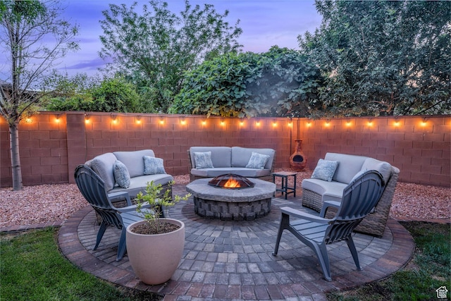 patio terrace at dusk with an outdoor living space with a fire pit and a fenced backyard