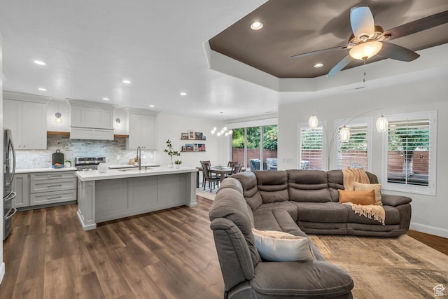 living room featuring a ceiling fan, dark wood-style flooring, recessed lighting, baseboards, and a chandelier