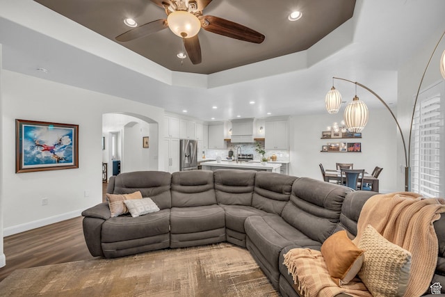 living area with arched walkways, wood finished floors, a ceiling fan, recessed lighting, and baseboards