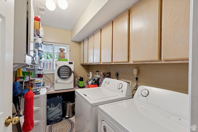 washroom featuring separate washer and dryer, cabinet space, and a textured ceiling