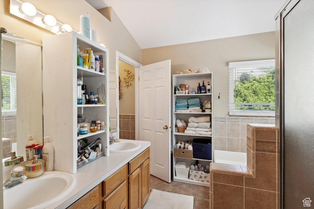 full bath with healthy amount of natural light, lofted ceiling, double vanity, and tile patterned flooring