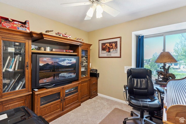 home office with light carpet, a ceiling fan, and baseboards