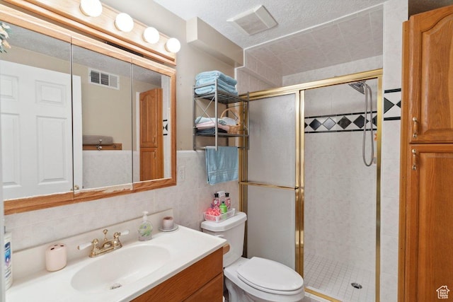 bathroom with a shower stall, vanity, toilet, and tile walls