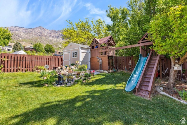 view of yard with a shed, a playground, an outdoor structure, and a mountain view
