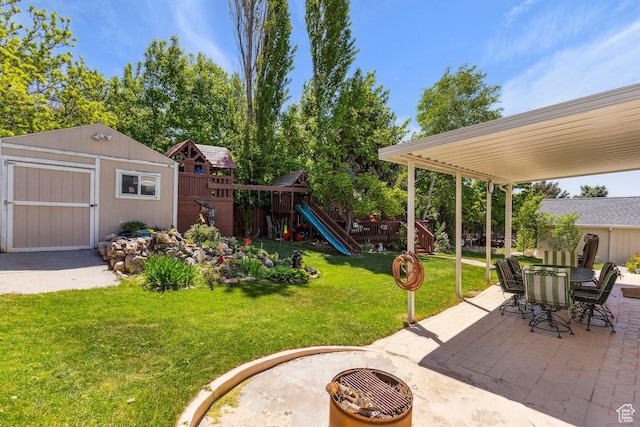 view of yard with a patio area, a playground, a shed, an outbuilding, and outdoor dining space