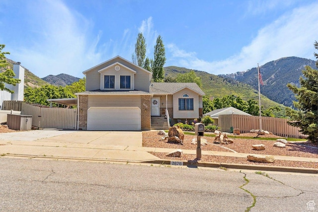 view of front of home with a mountain view, a garage, fence, concrete driveway, and brick siding