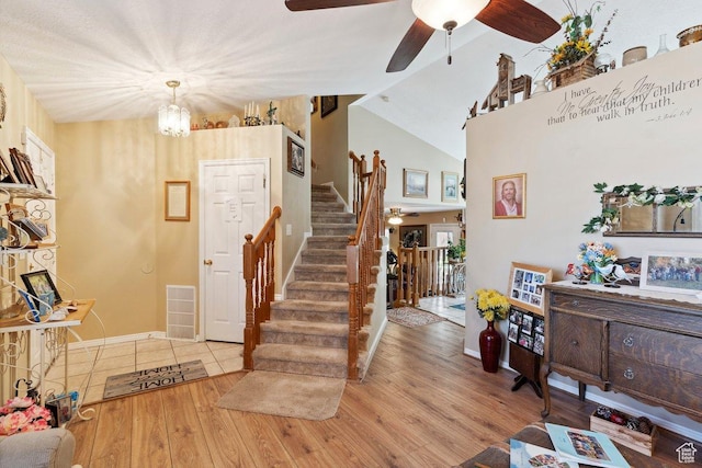 foyer with ceiling fan, stairs, wood finished floors, baseboards, and lofted ceiling