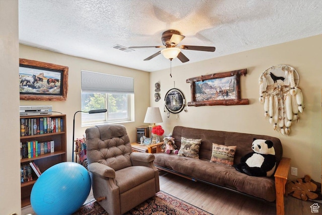 living room featuring a ceiling fan, wood finished floors, and a textured ceiling