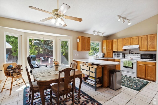 kitchen with white electric range oven, under cabinet range hood, stainless steel microwave, track lighting, and light tile patterned flooring