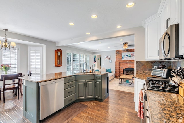 kitchen with appliances with stainless steel finishes, a sink, white cabinets, wood-type flooring, and recessed lighting