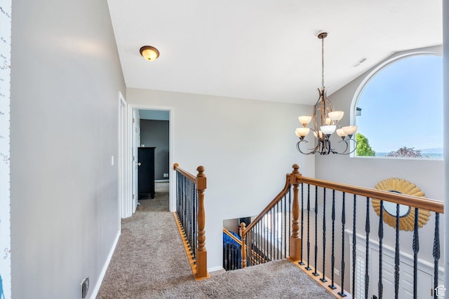 hallway with an upstairs landing, lofted ceiling, carpet, a chandelier, and baseboards