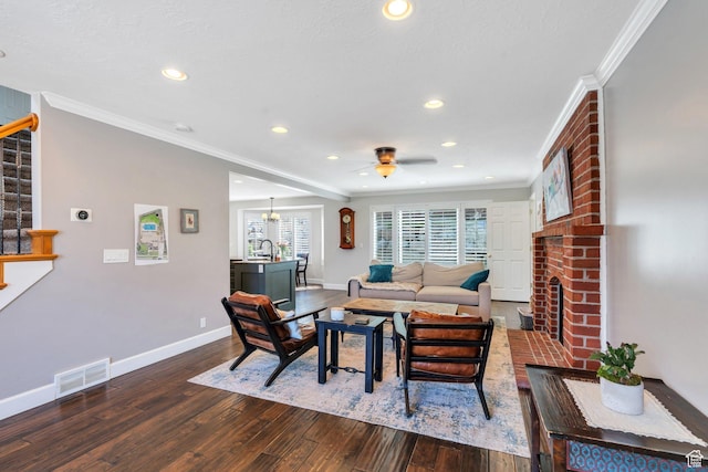 living room with crown molding, hardwood / wood-style floors, baseboards, a ceiling fan, and a brick fireplace