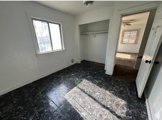 unfurnished bedroom with multiple windows, a closet, and baseboards