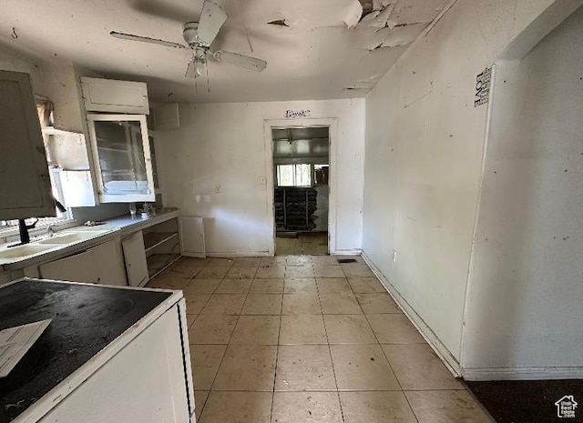 kitchen with a sink, white cabinets, a ceiling fan, and light tile patterned floors