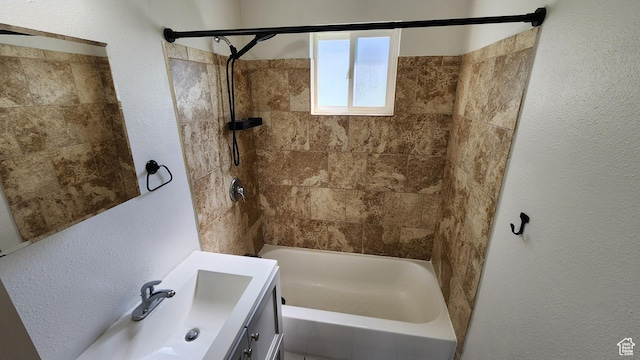 bathroom with bathing tub / shower combination, vanity, and a textured wall