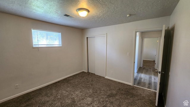 unfurnished bedroom with a closet, carpet floors, baseboards, and a textured ceiling