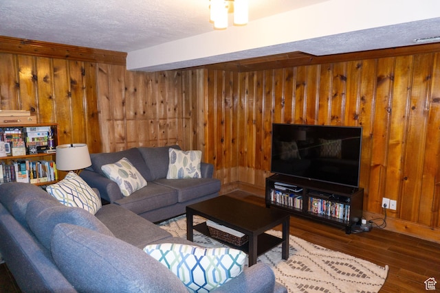 living area featuring hardwood / wood-style flooring, wooden walls, and a textured ceiling