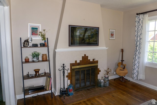 living room with wood finished floors, a fireplace with flush hearth, baseboards, and plenty of natural light